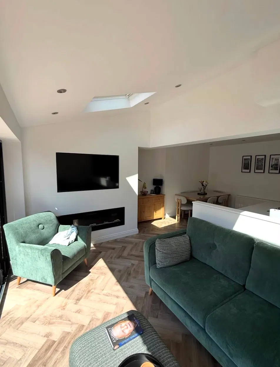 Bright open-plan living room with skylight, herringbone floors and green sofas